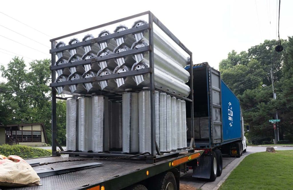 Boxwell roll up doors wrapped in foam and loaded into a metal packing rack.