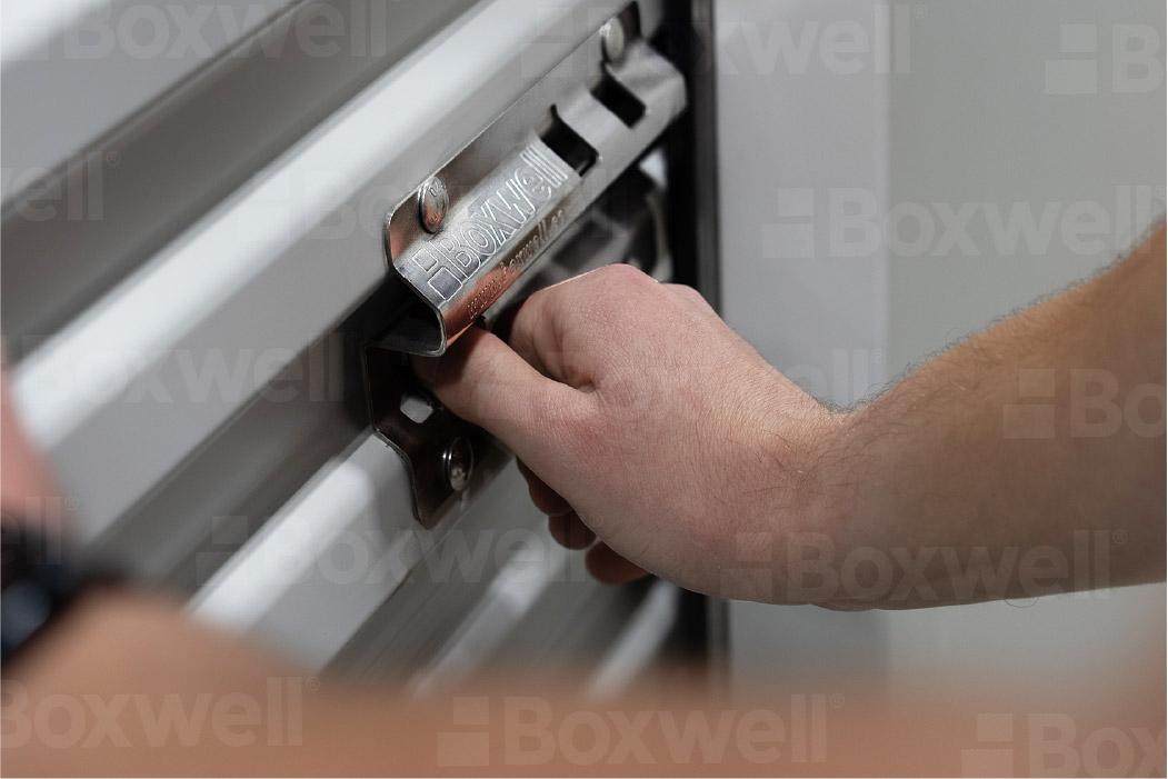 Close-up of a person unlocking a high-quality, durable roll-up door on a Boxwell hallway system storage unit. Featuring a secure, ergonomic latch mechanism designed for ease of use and long-term reliability. Ideal for self-storage facilities looking for premium hallway storage solutions.”